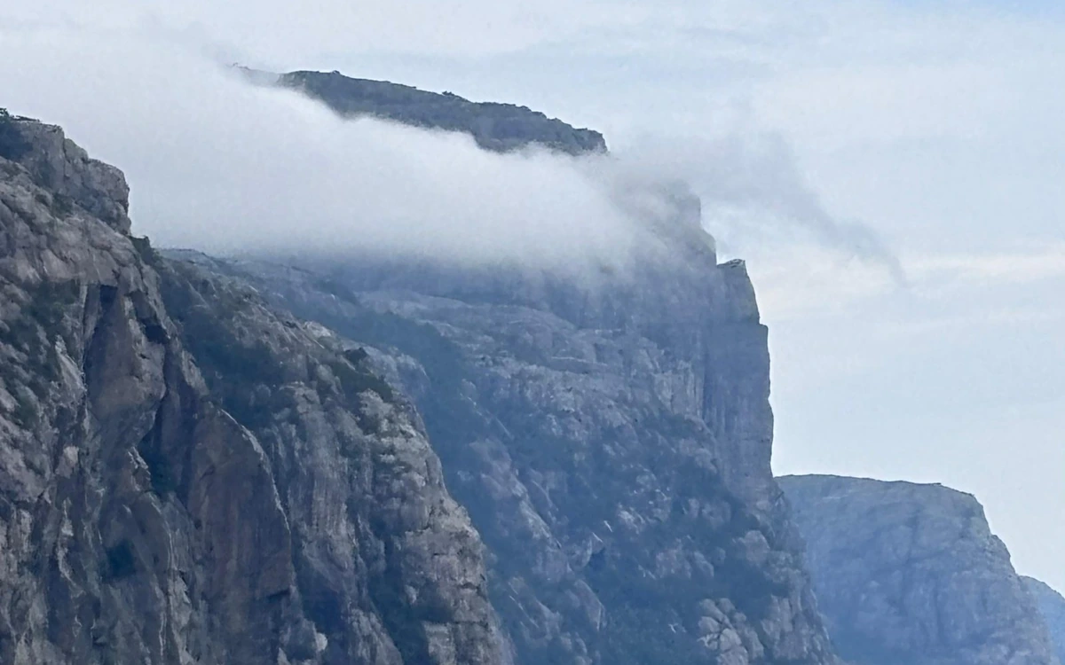 A band of cloud lying across the top of grey fjord cliffs