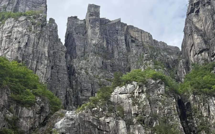 Jagged grey rock towers and green scrub seen from below