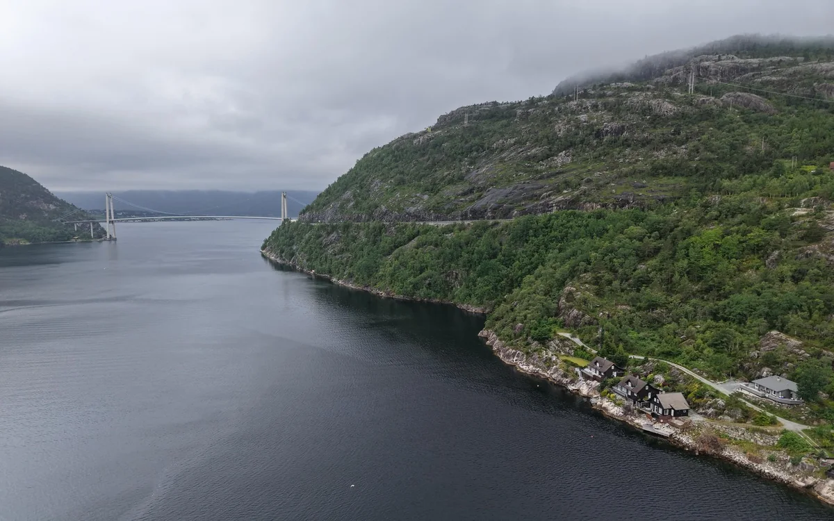 A suspension bridge spanning the entrance to a narrow fjord