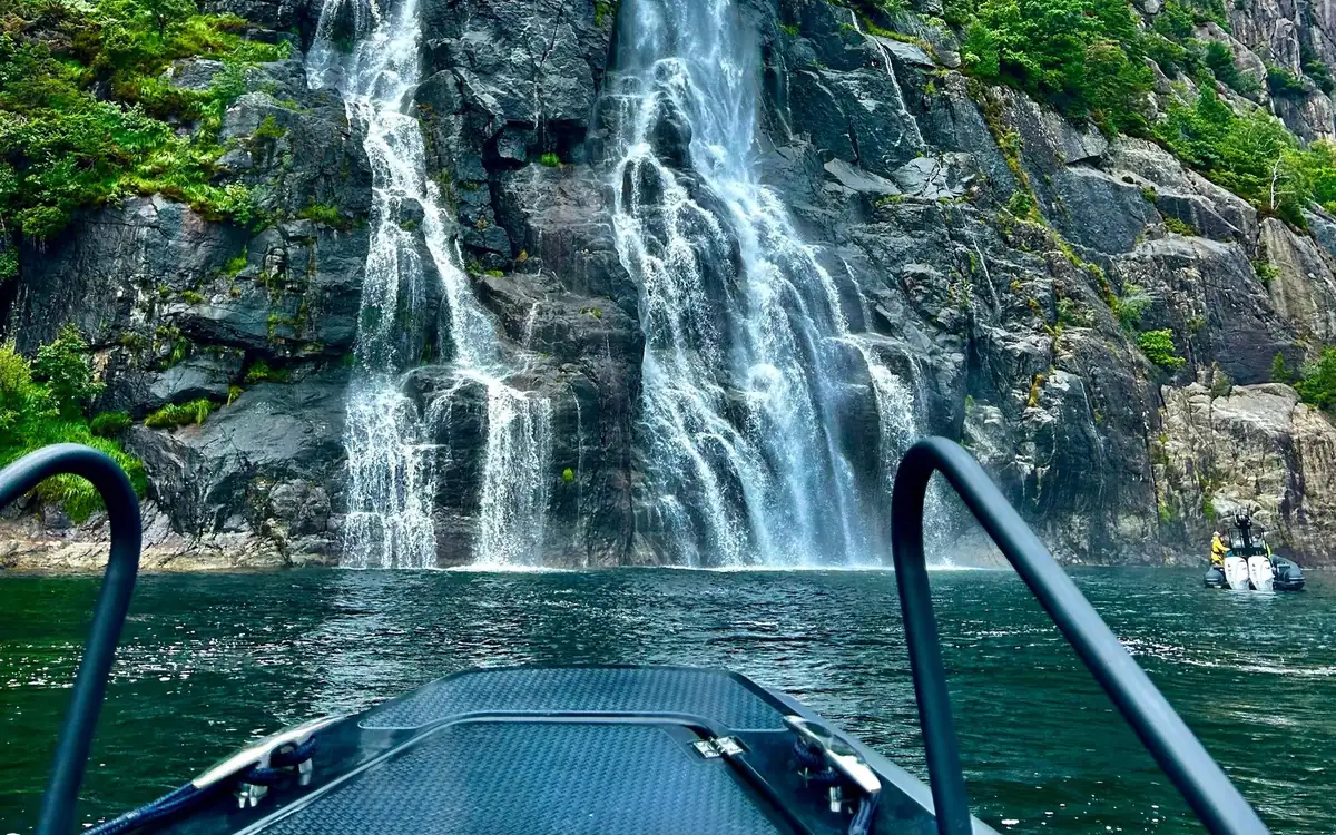 A waterfall seen over the bow rail of a small boat